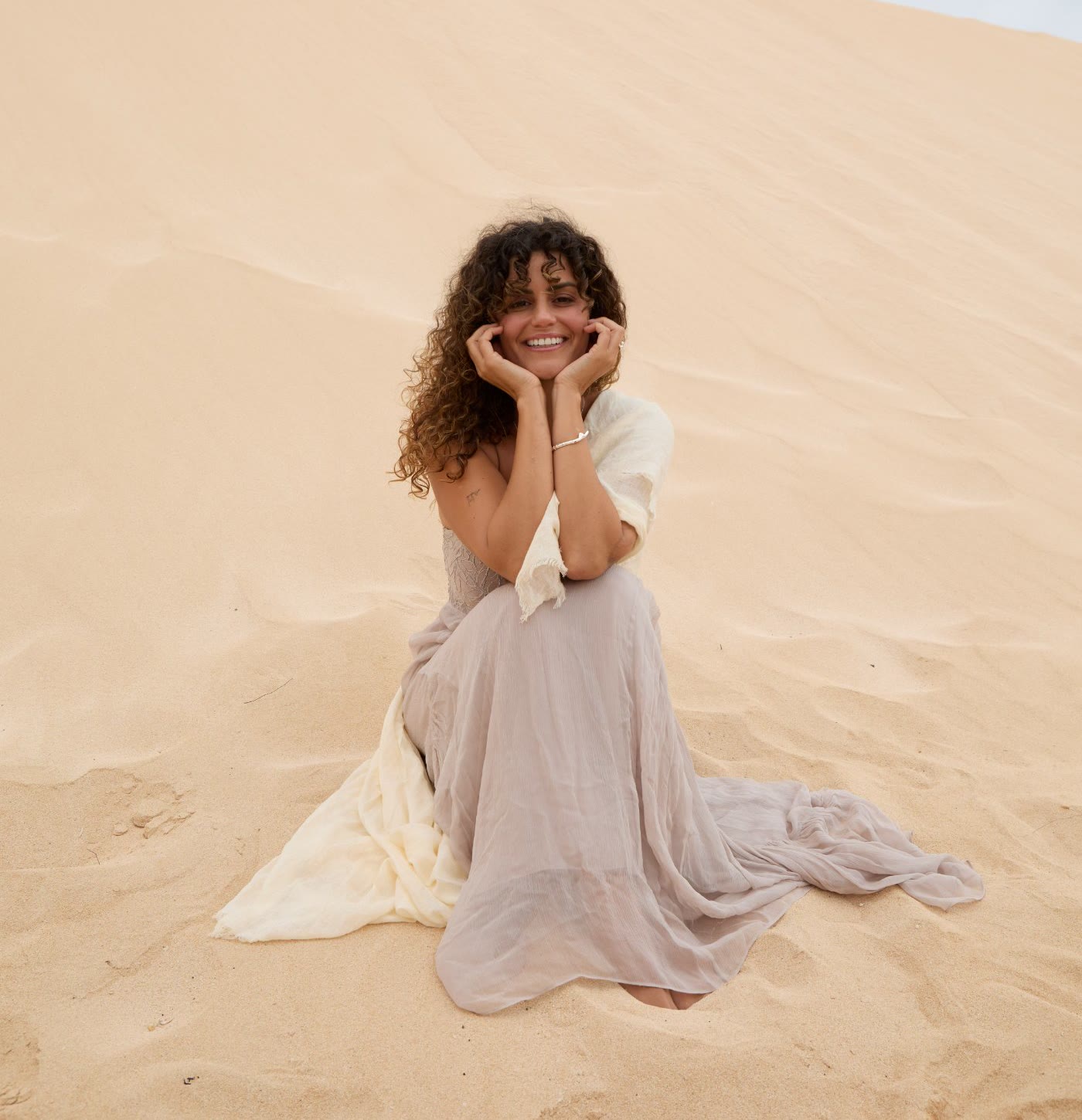 Lola Ortiz, fundadora de El Diario Rosa, sentada en las dunas de Fuerteventura